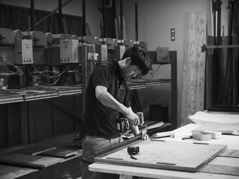 白井工場で作業台の木材にビスを打つ職人