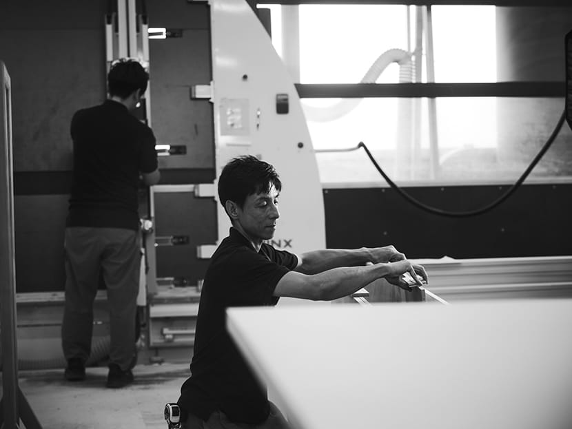 白井工場で白いパネルを加工する職人